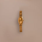 The Slim Oval Timepiece gold wristwatch with a polished link bracelet is shown against a plain beige background.