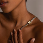 The Azteca Link Timepiece in Mixed Metal features a minimalist champagne dial, showcased on a gold wristwatch resting elegantly against a woman's bare shoulder as her hand traces her collarbone.