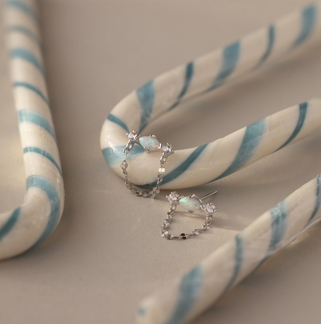 Flatlay of our Opal & Diamond Chain Studs against white and blue striped candy canes