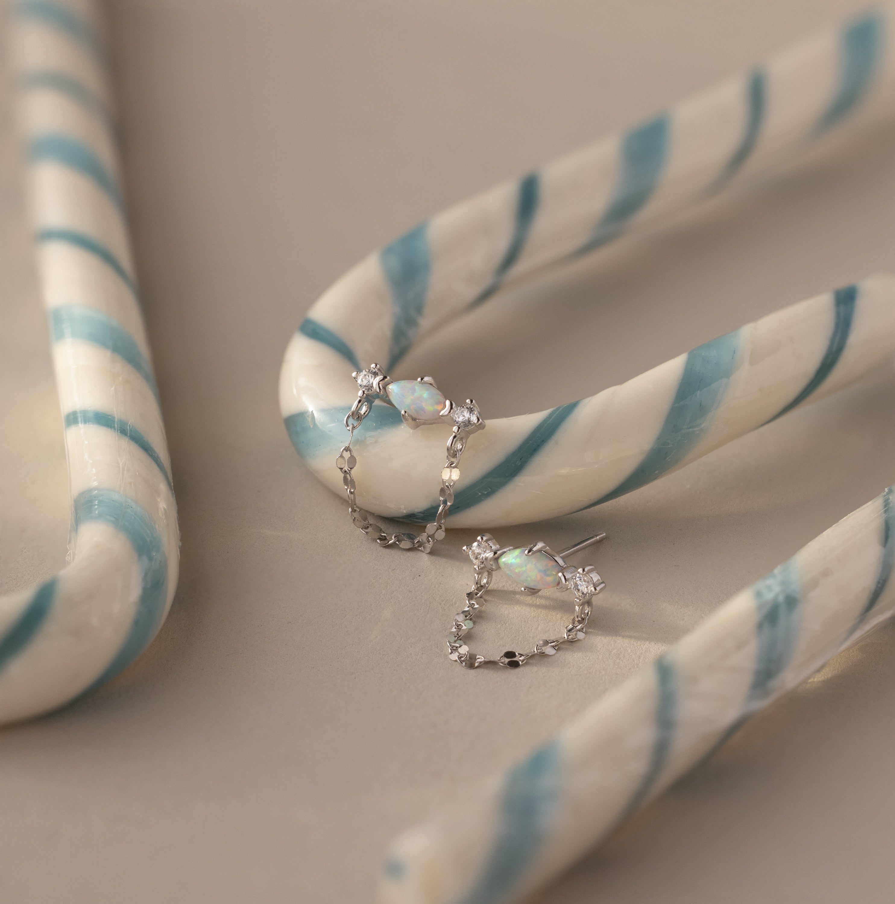 Flatlay of our Opal & Diamond Chain Studs against white and blue striped candy canes