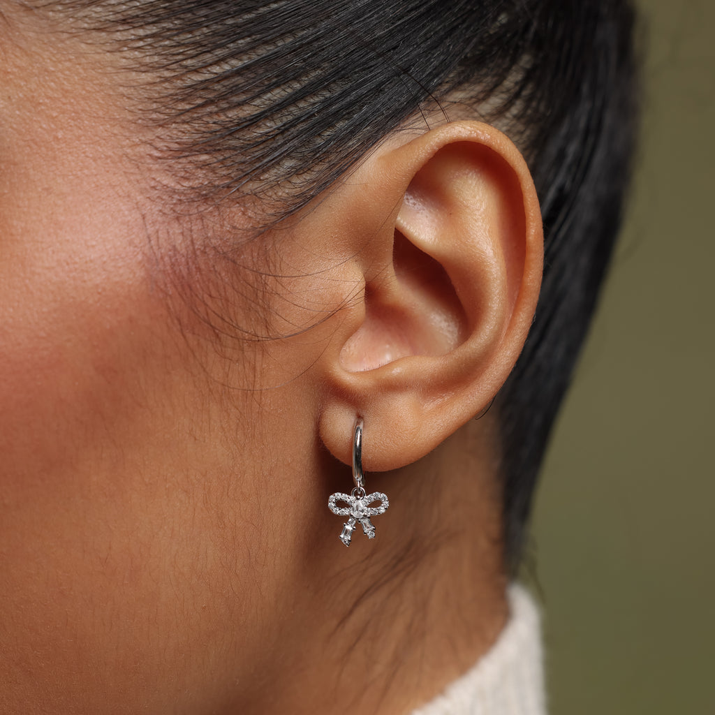 Close-up of an ear wearing our Pave Bow Charm Hoops earring