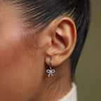 Close-up of an ear wearing our Pave Bow Charm Hoops earring