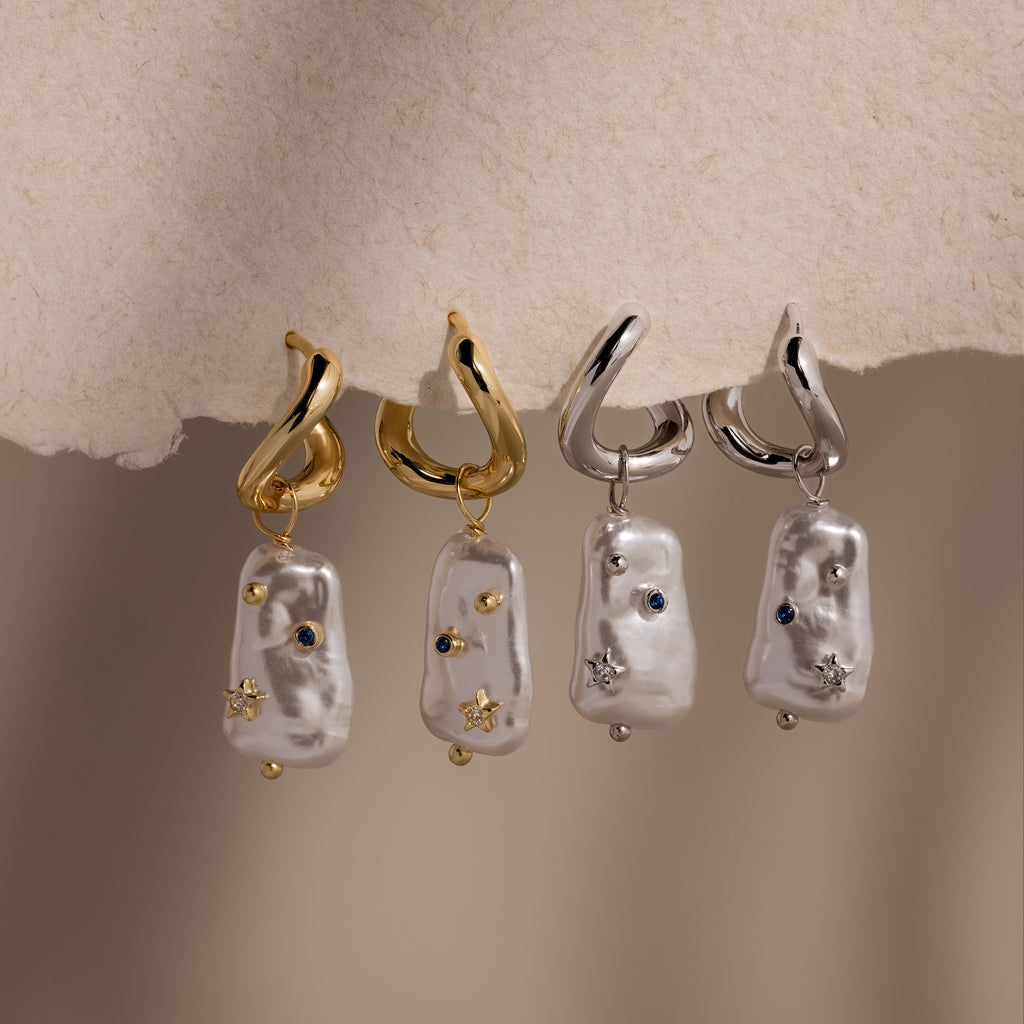 Two pairs of Starry Baroque Pearl Charm Hoops in White Gold, featuring silver accents, dangling irregular baroque pearl charms, and small gemstones.