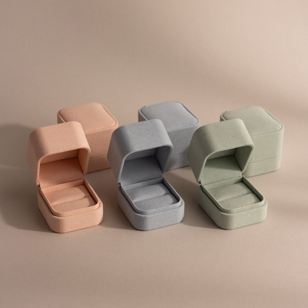 Three pastel-colored Suede Ring Boxes—pink, blue, and green—are shown open with matching closed boxes behind them, creating a chic, minimalist display.