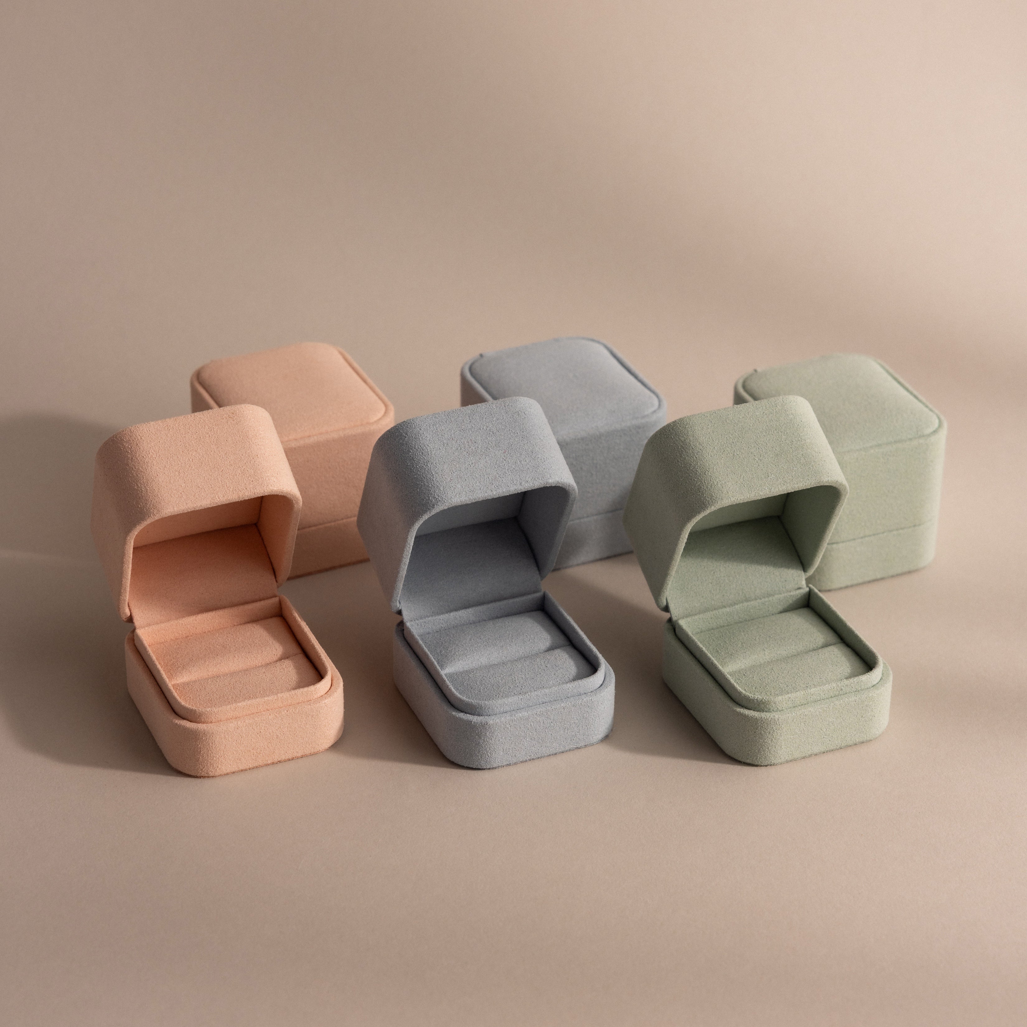 Three pastel-colored Suede Ring Boxes—pink, blue, and green—are shown open with matching closed boxes behind them, creating a chic, minimalist display.