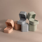 Three pastel Suede Ring Boxes in peach, gray, and green are open and stacked on a neutral background, showcasing their minimalist design.