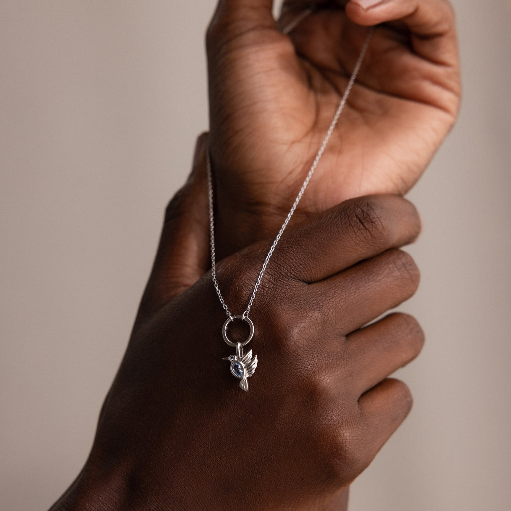 A person holds the Hummingbird Charm in Sterling Silver, featuring a delicate design and a subtle diamond accent, making it a truly meaningful gift.