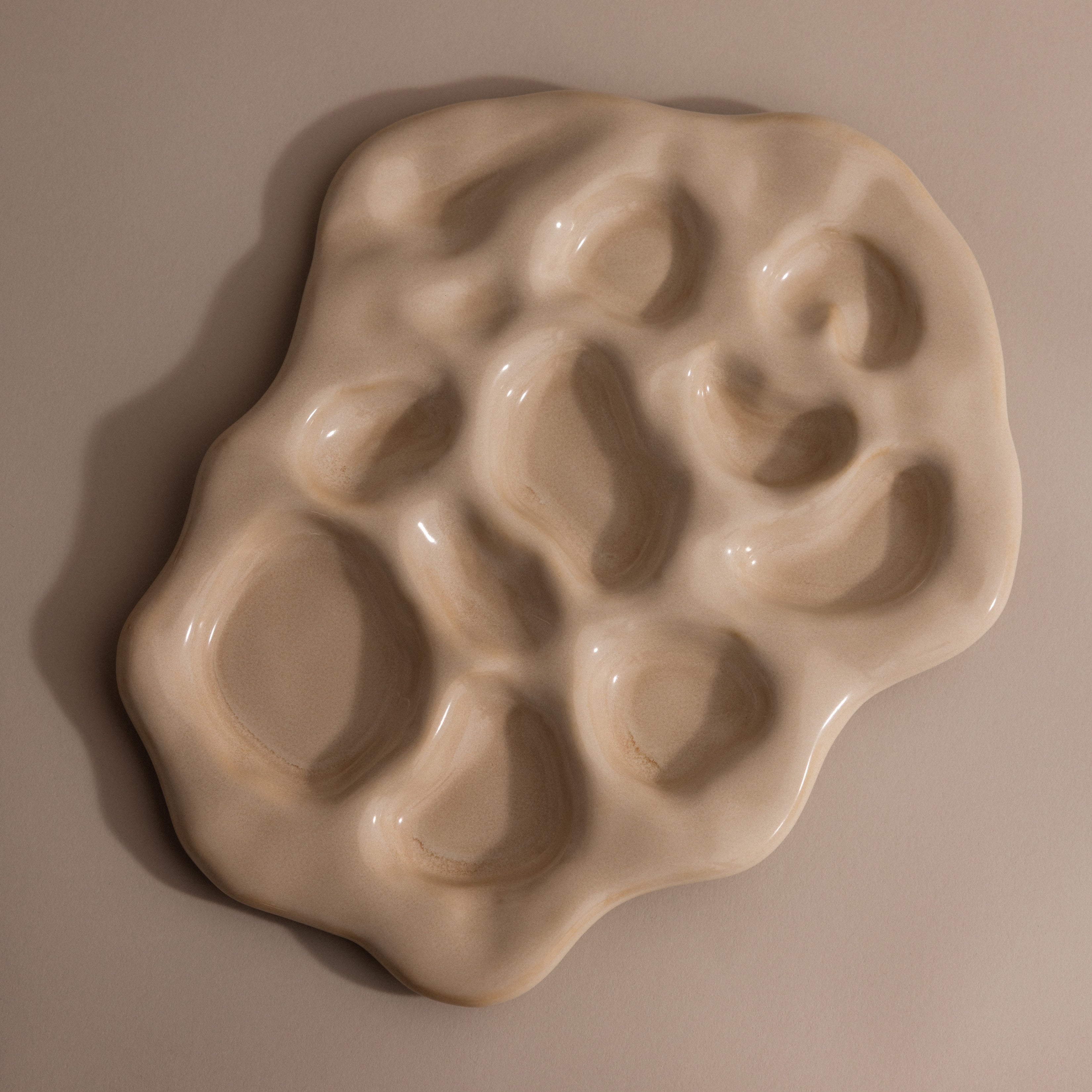 The Organic Treasure Trove Jewelry Dish is an irregular beige ceramic piece featuring multiple rounded indentations, ideal for displaying minimalist or organic jewelry against a neutral backdrop.