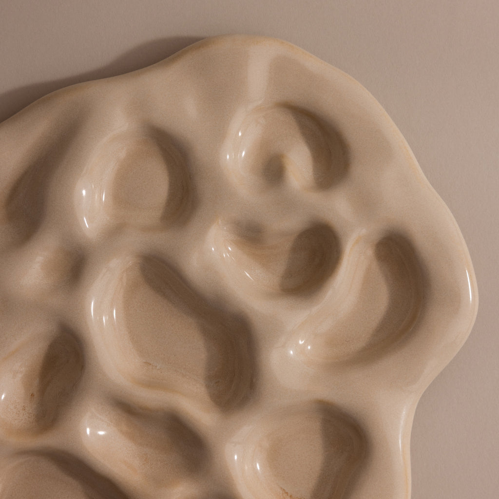 The Organic Treasure Trove Jewelry Dish features a cream-colored ceramic design with wavy edges and multiple oval indents, perfect for displaying your favorite pieces on any beige surface.