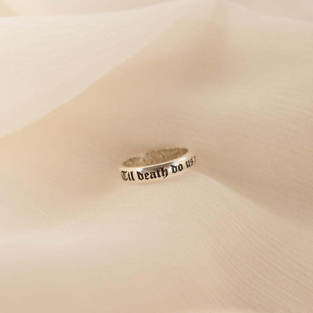 A Half Round Fingerprint Ring rests on soft, beige fabric.