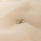 A Half Round Fingerprint Ring rests on soft, beige fabric.
