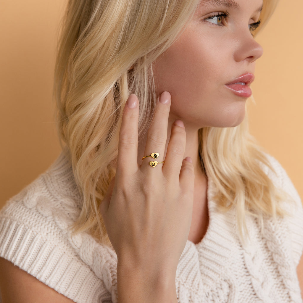 Blonde woman in a cream sweater displays the Paw Print Duo Heart Ring featuring heart-shaped details—an ideal gift for pet lovers.