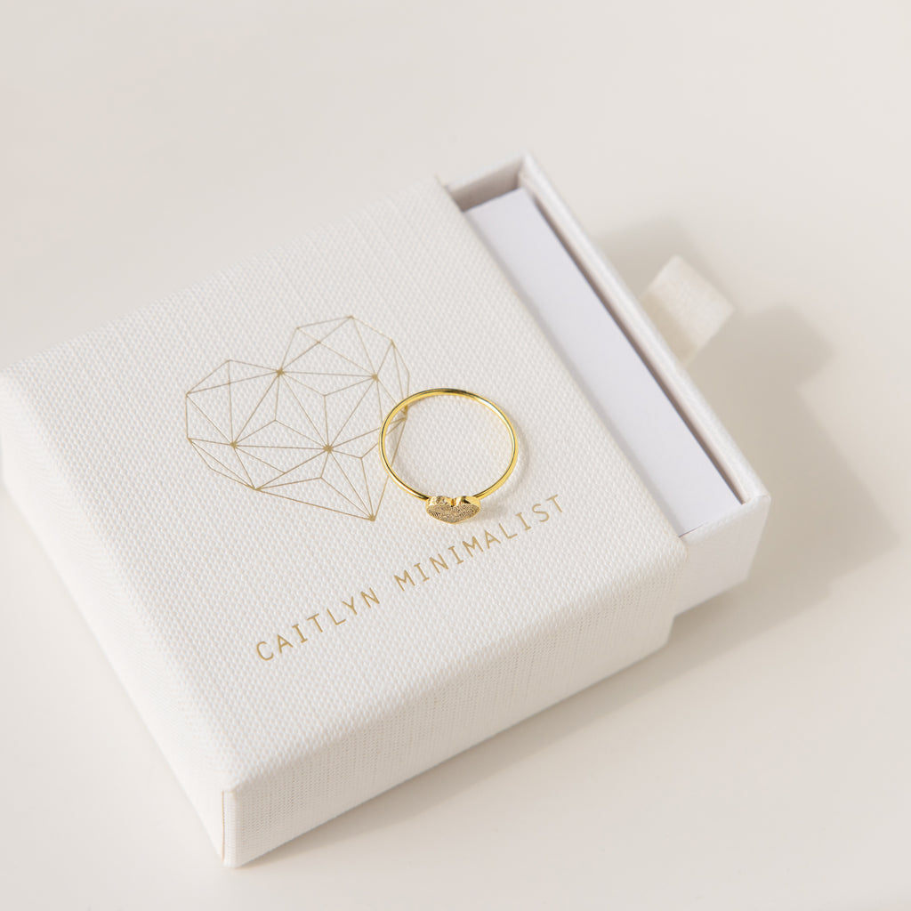 The Fingerprint Heart Ring sits on a white Caitlyn Minimalist box, showcasing its unique geometric heart—an ideal custom jewelry piece for anyone seeking a personal touch.