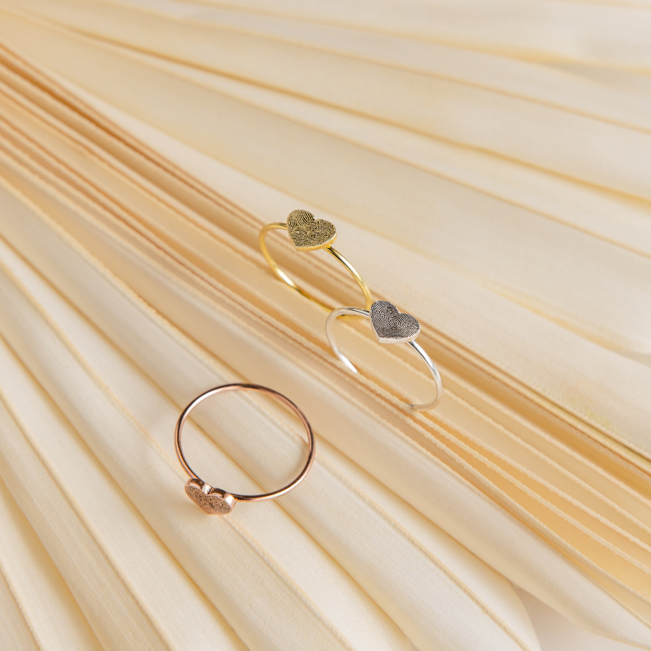 The Fingerprint Heart Ring is displayed on soft, cream-colored pleated fabric, highlighting the elegance of personalized jewelry.
