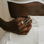 Close-up of a hand wearing the Mothers Birthstone Ring, resting on white high-waisted pants near a bare midriff.