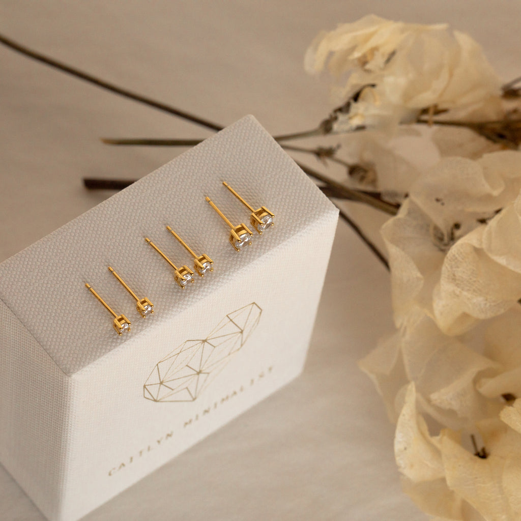 The Booker Diamond Studs Set is displayed on a white box with dried flowers in the background—perfect lightweight earrings to elevate your everyday jewelry collection.