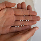 A hand displays the Booker Diamond Studs Set—four pairs of diamond studs in increasing sizes, perfect as lightweight earrings for everyday wear.