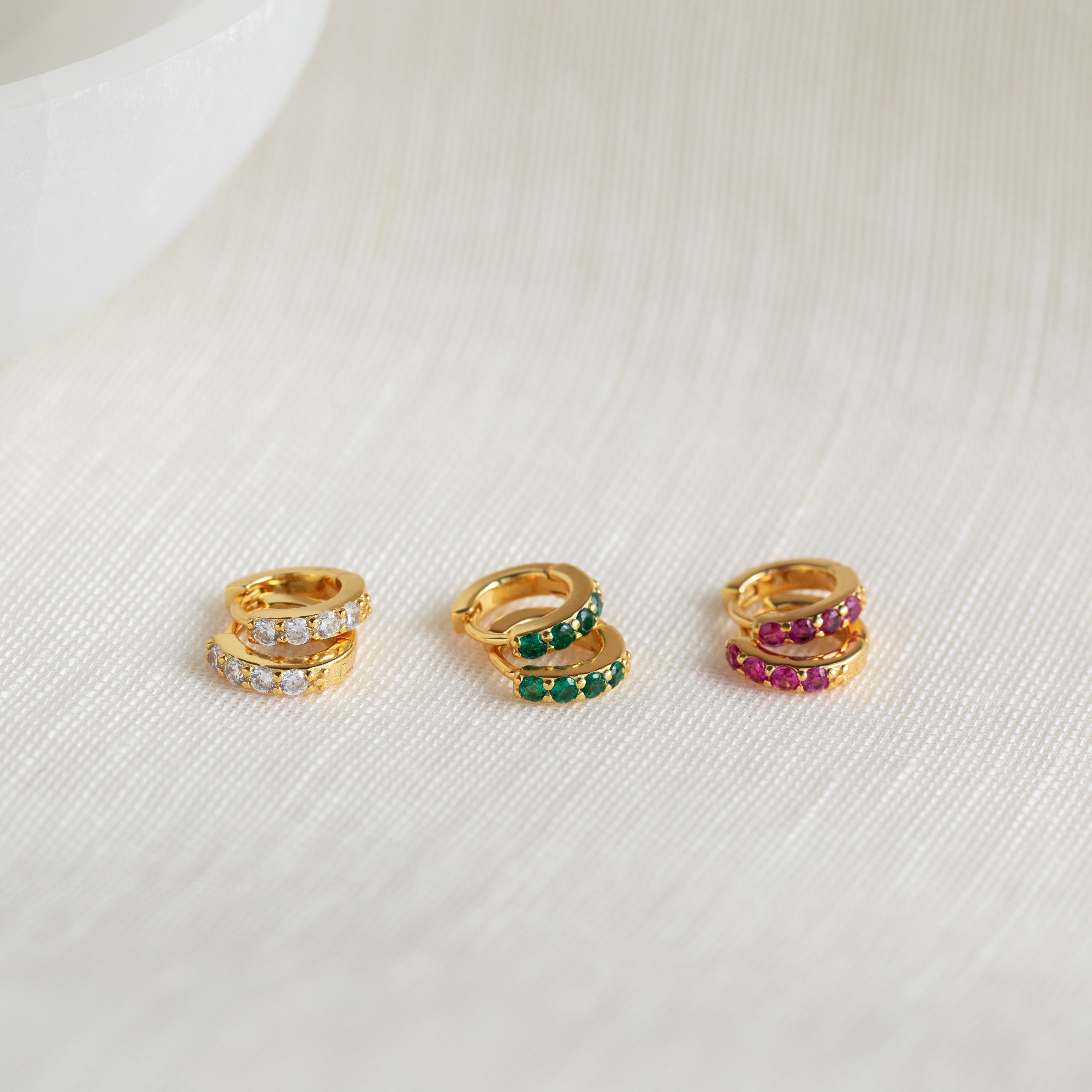 The Elise Emerald Huggies feature striking green gemstones in a gold setting—ideal for adding bold color and elegance to your jewelry collection on any occasion.