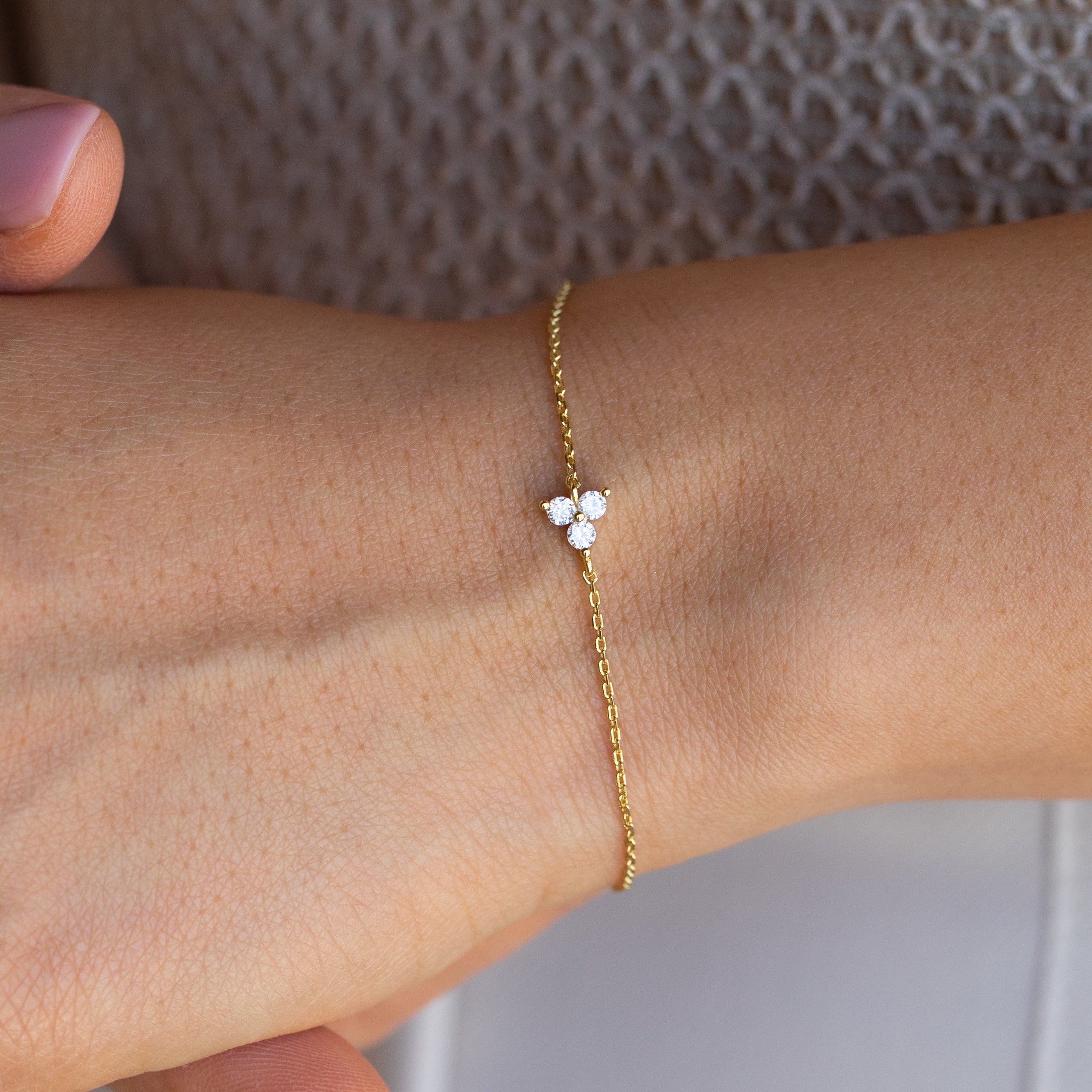 The Lily Diamond Bracelet features a delicate gold chain with a small three-diamond cluster, making it the perfect touch of subtle elegance for evening wear.