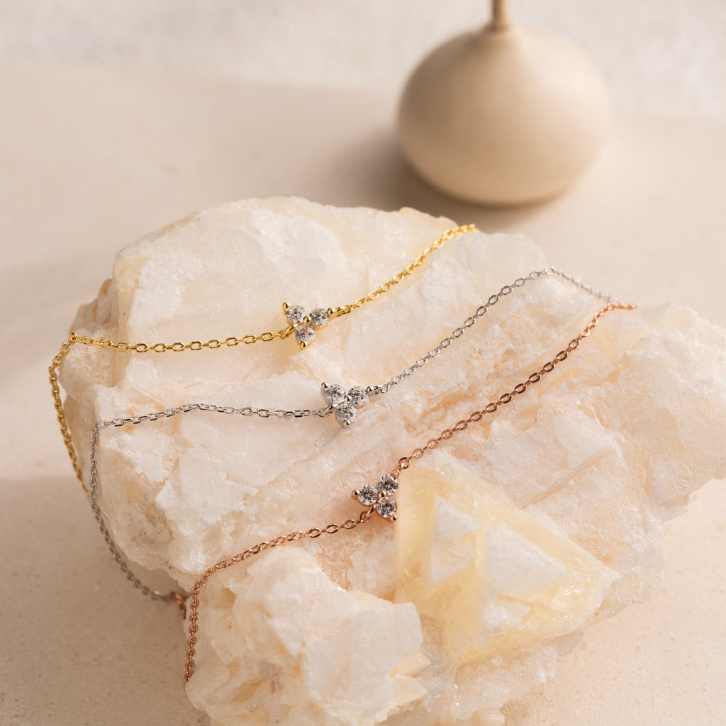 The Lily Diamond Bracelet features a delicate chain in gold, silver, or rose gold, each adorned with a sparkling diamond accent to beautifully elevate your evening look.