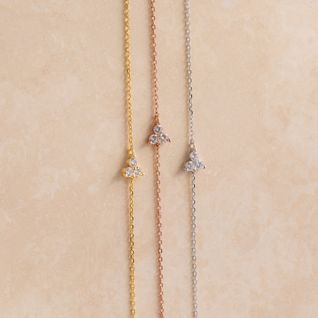 The Lily Diamond Bracelet features three delicate chains in gold, rose gold, and silver, each adorned with a small three-stone diamond cluster—perfect for adding subtle sparkle to your evening attire.