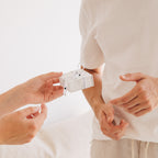 Two people exchange a small white gift box in a bright, minimalist setting—the perfect way to present the Handwriting Dog Tag Keychain for Father’s Day.