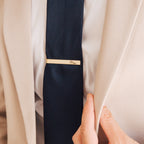 A person in a beige suit with a navy tie and the Handwriting Tie Clip engraved with "Groom," making it the perfect personalized gift.