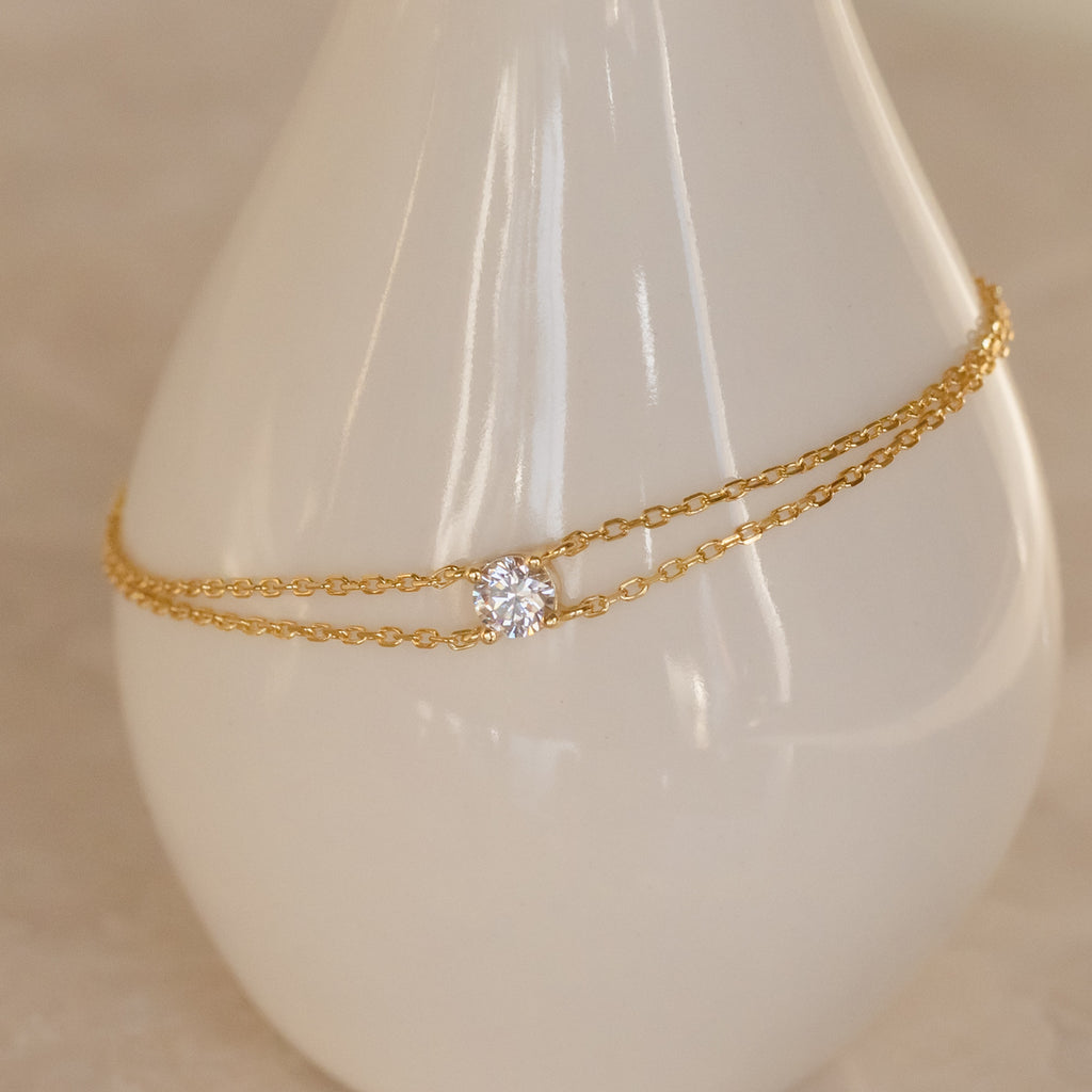 Elegant Duo Chain Diamond Bracelet with a minimalist gold design and single round diamond, showcased on a white vase—an ideal anniversary gift.