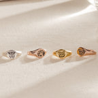 The Pet Signet Ring showcases four engraved rings with dog and cat faces on a textured surface—ideal as a custom pet ring or a heartfelt memorial pet gift.