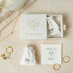 Old English Name Necklace in Curb Chain displayed on a beige surface, styled with minimalist jewelry boxes, rings, personalized charms, and pouches.