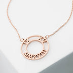 The Roman Numerals Necklace features a rose gold circular pendant with numerals cut out along the edge—a timeless milestone jewelry piece.