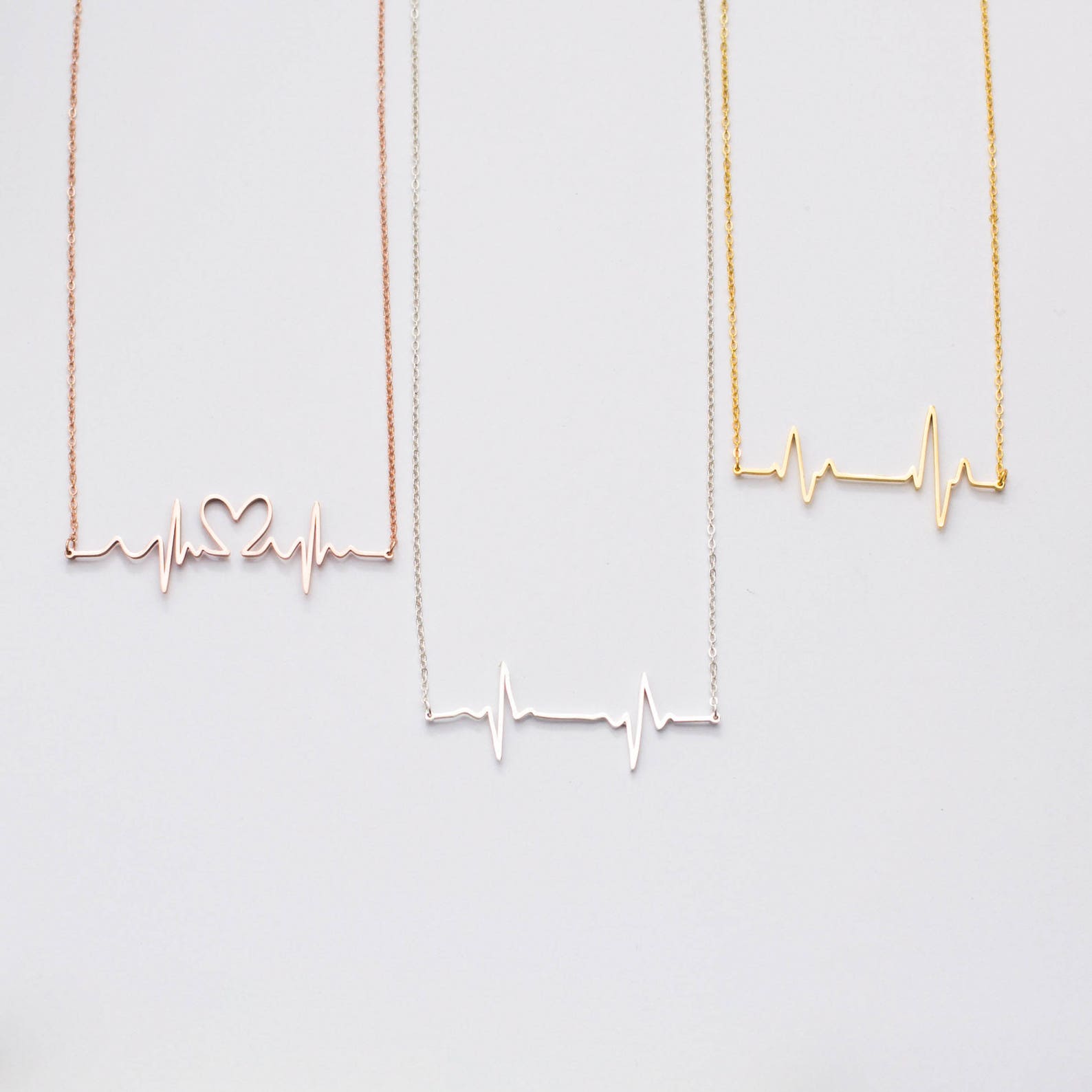 The Heartbeat Necklace features three pendants—one heart-shaped, one plain, and one gold—making it a unique piece of voice jewelry and a thoughtful personalized gift.