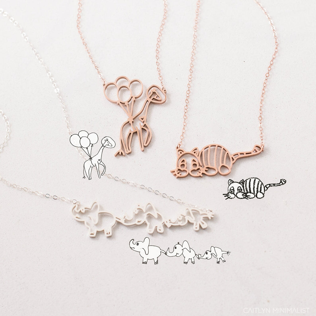The Kids Drawing Necklace in Rose Gold features delicate animal-themed line art—balloons, a cat, and elephants—a unique piece of wearable art and the perfect personalized gift.