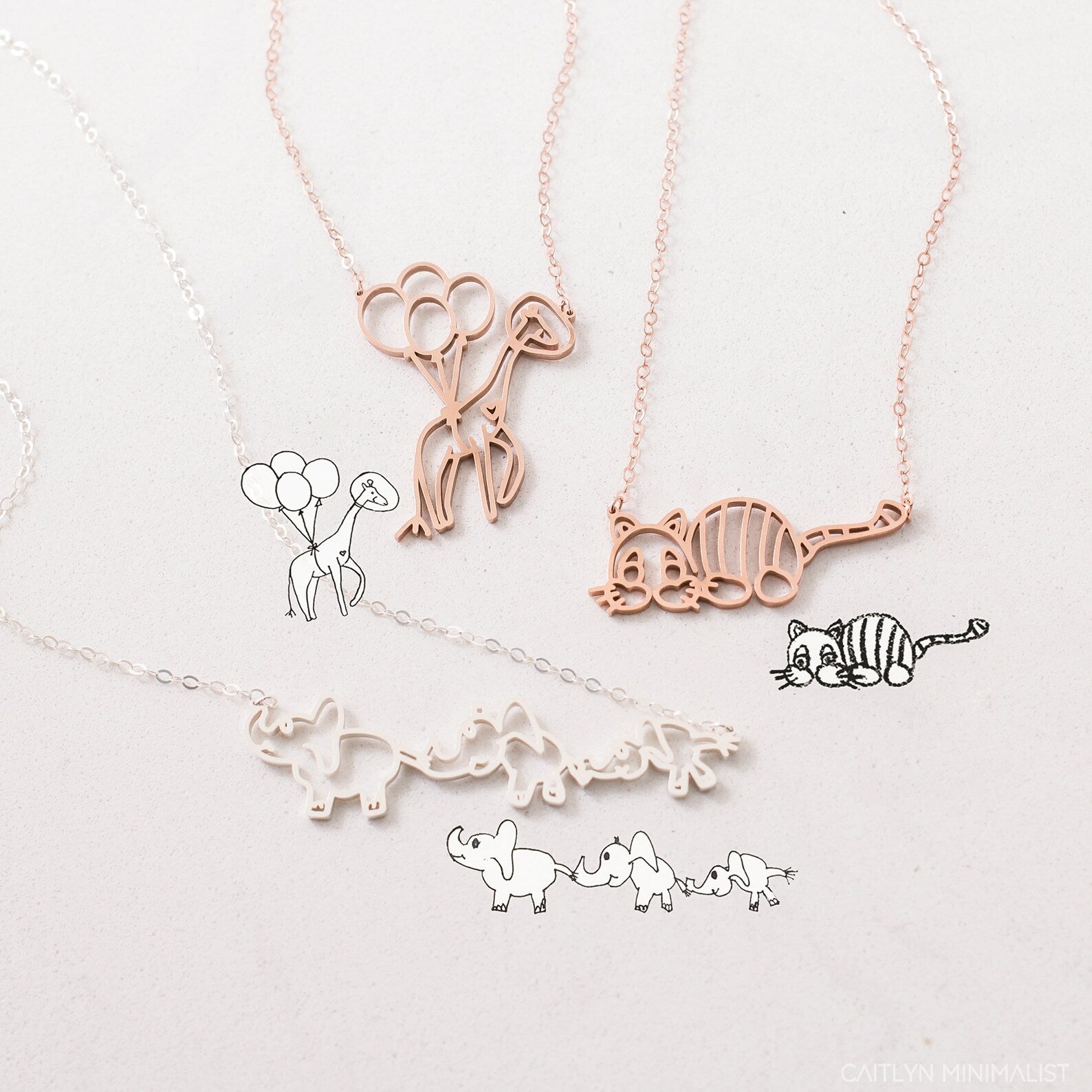 The Kids Drawing Necklace in Rose Gold features delicate animal-themed line art—balloons, a cat, and elephants—a unique piece of wearable art and the perfect personalized gift.