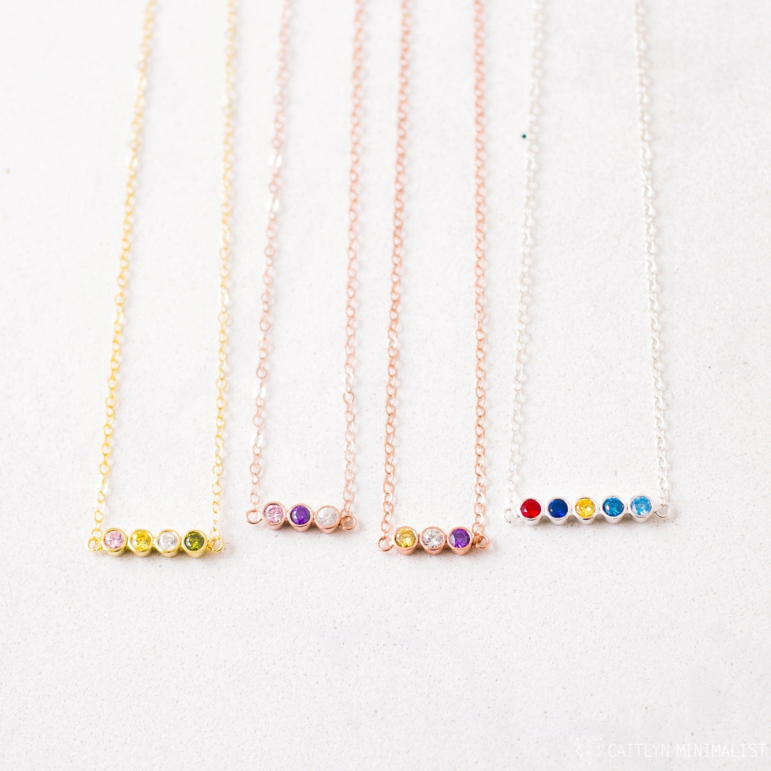 Four delicate chain necklaces, each with four colorful gemstone beads, displayed side by side—Multiple Birthstone Necklace, the perfect personalized gift for new moms or anyone wanting a meaningful custom birthstone necklace.