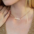 A woman wears an Old English Name Necklace with "Elizabeth" stylishly crafted in elegant script letters.