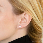 Close-up of a woman's ear wearing Alex Initial Studs—small, silver earrings perfect for lovers of dainty and personalized initial jewelry.