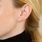 A close-up of a woman's ear adorned with Alex Initial Studs.
