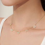 Dainty gold necklace featuring five pave crystal butterfly charms evenly spaced along a delicate chain, worn just above the collarbone for an elegant, minimalist look.