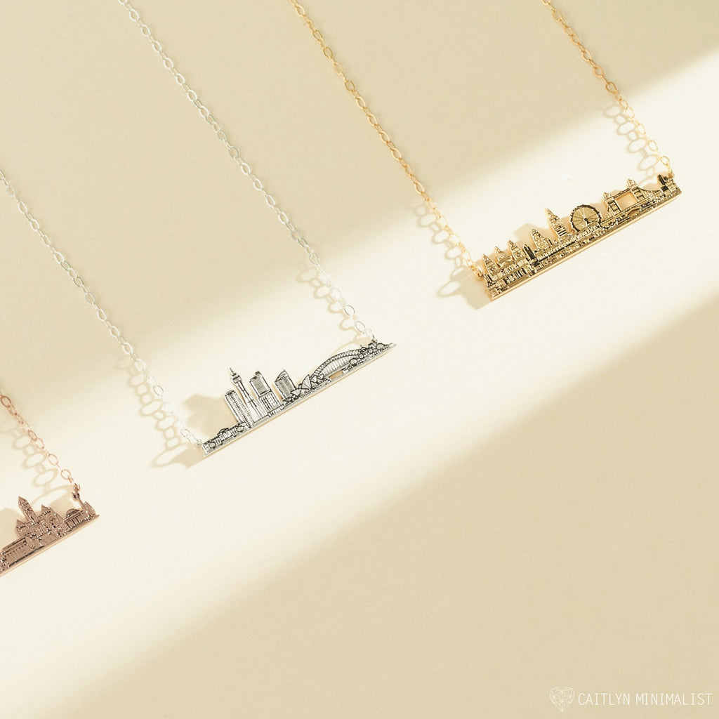 The City Skyline Necklace is available in gold, silver, and rose gold, shown on a beige background—an elegant and personalized cityscape necklace, perfect as a thoughtful gift.