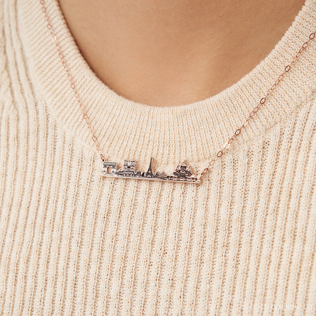 A person wearing a cozy cream knit sweater and the City Skyline Necklace, creating a stylish, personalized gift idea.