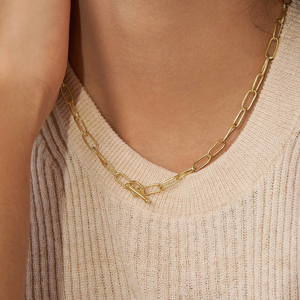 A woman models the Paperclip Toggle Necklace with a light beige ribbed sweater, highlighting an easy boho-chic style.