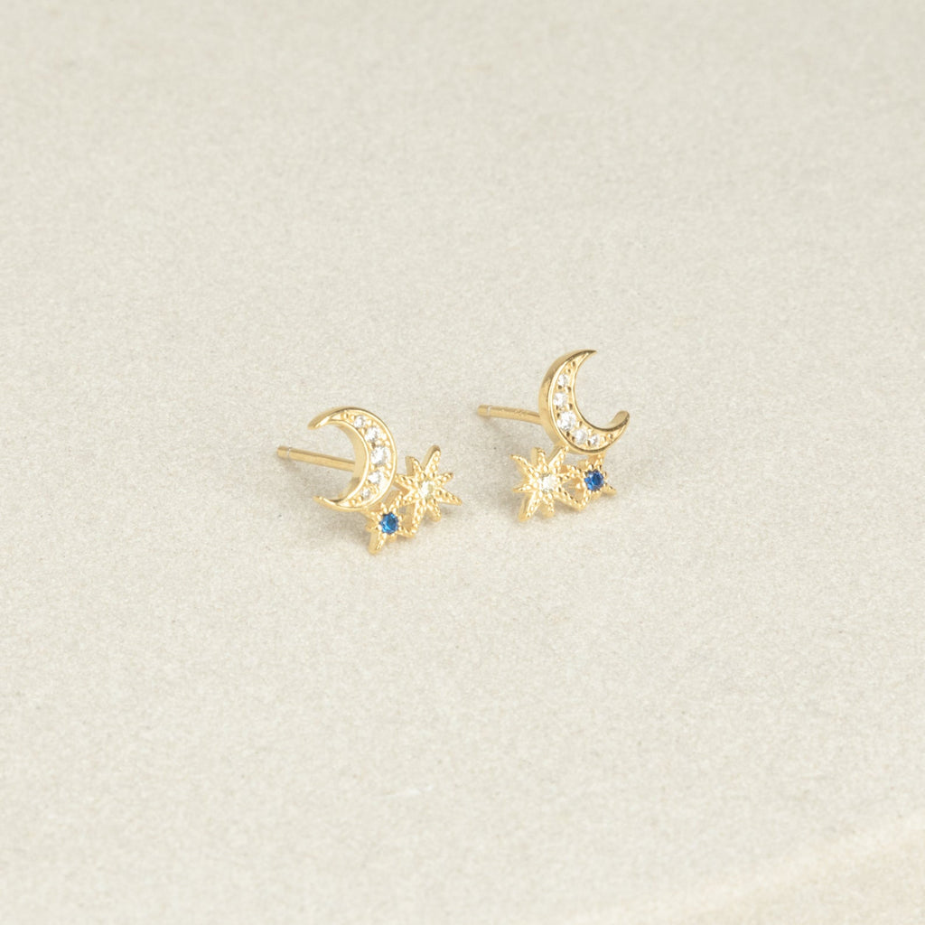 The Aeon Studs feature gold constellations with crescent moons, star shapes, and sapphire accents that bring celestial charm to any neutral backdrop.