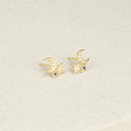 The Aeon Studs feature gold constellations with crescent moons, star shapes, and sapphire accents that bring celestial charm to any neutral backdrop.