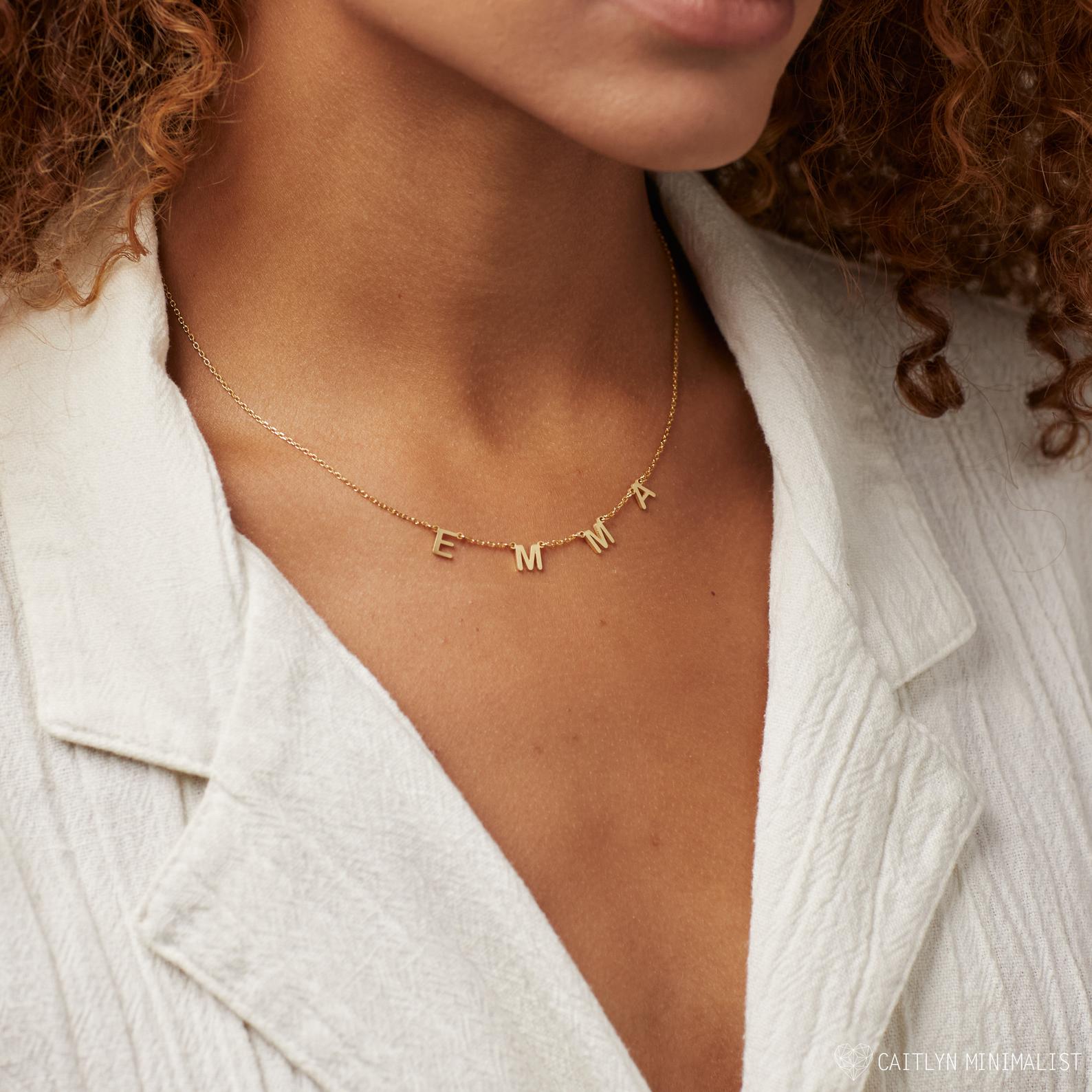 Woman wearing a Custom Letter Necklace in Rose Gold spelling EMMA, paired with a white textured blazer—an elegant approach to personalized jewelry.