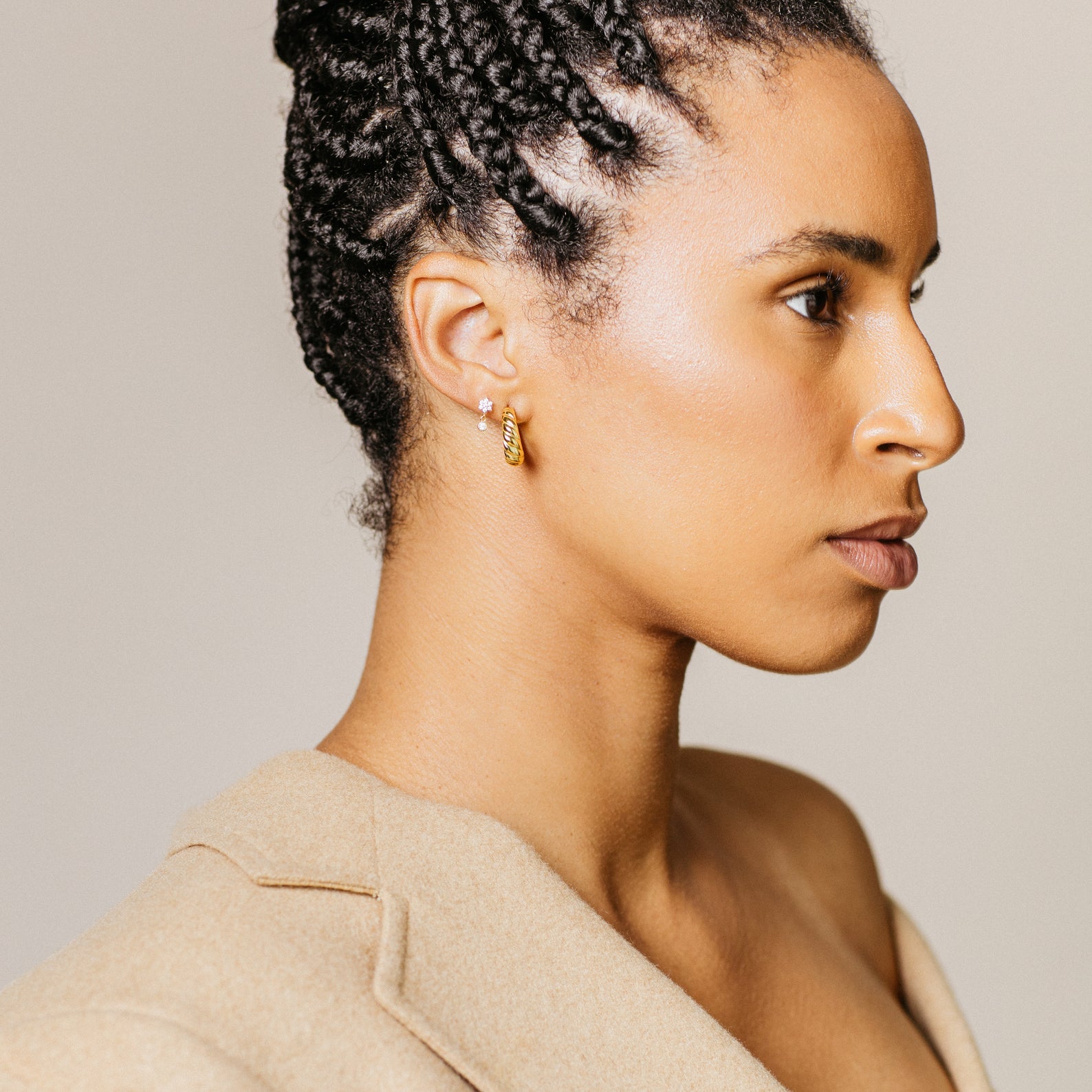 Woman with braided hair, facing right, wears dainty Lexi Flower Studs and a beige blazer.