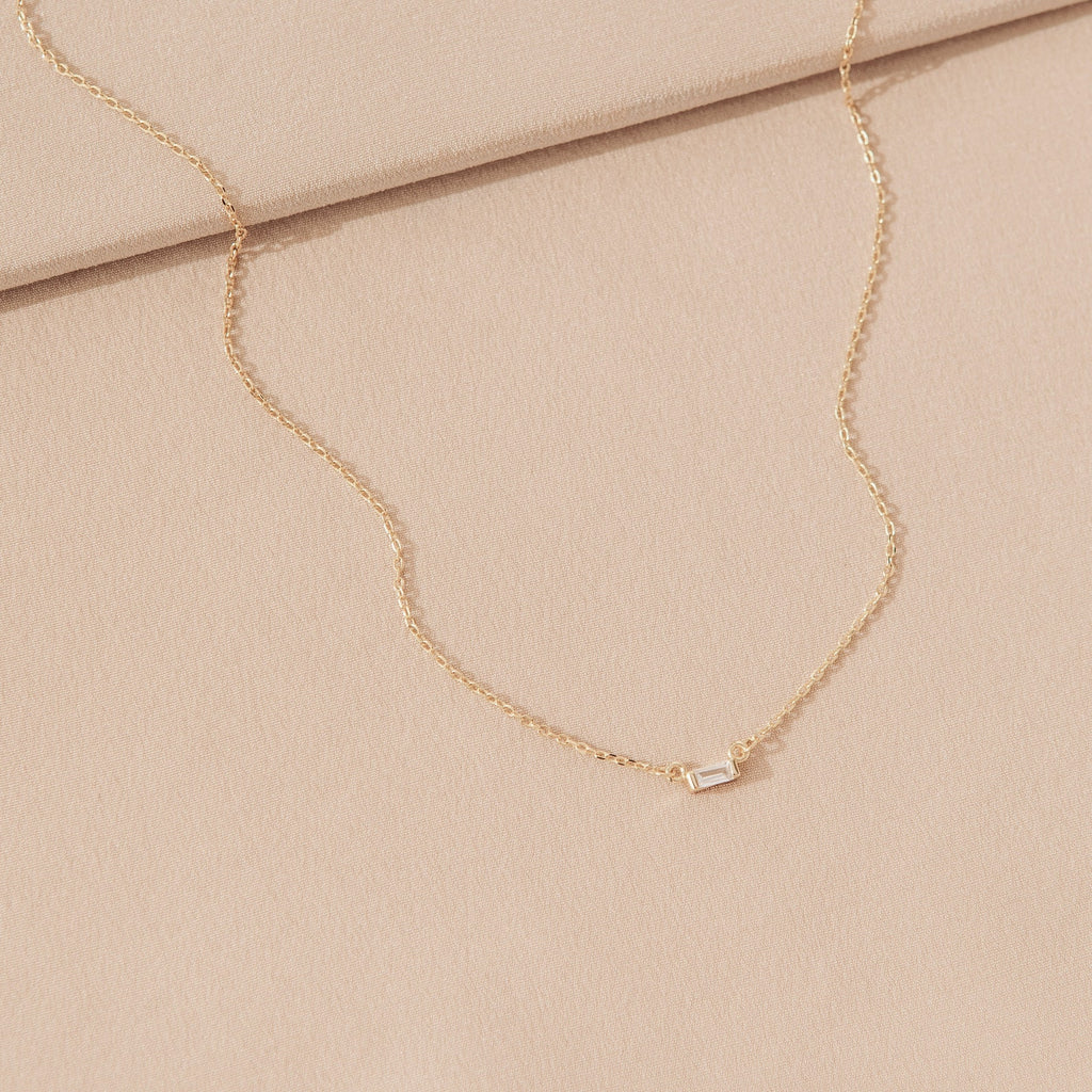 Delicate sterling silver Emery Necklace with a small rectangular pendant on a soft beige fabric—a perfect minimal accessory and thoughtful holiday gift.