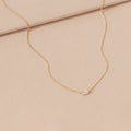 Delicate sterling silver Emery Necklace with a small rectangular pendant on a soft beige fabric—a perfect minimal accessory and thoughtful holiday gift.