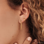 Close-up of a woman's ear with Curb Chain Studs and a classic hoop earring peeking through curly hair—an elegant and personal gift idea.