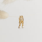 Mae Huggies: Elegant gold pearl earrings with sparkling crystals, delicately hanging on a string against a light background.